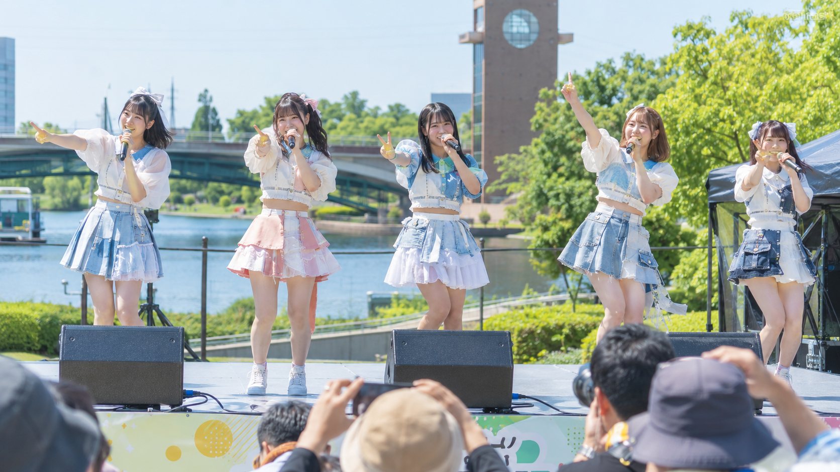 水辺のステージで歌うアイドルグループ